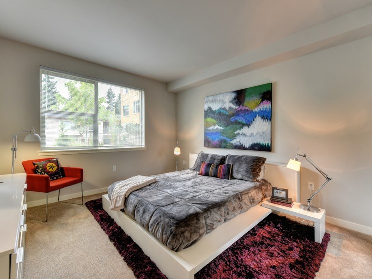 Bedroom with Large Window, Carpet, Red/Black Rug, Abstract Painting on Wall and Low Elevated Mattress